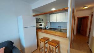 a small kitchen with a white refrigerator and wooden counters at Balcon al mar in Bellreguart