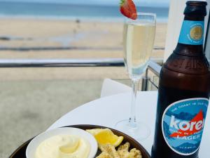 a plate of food with a bottle of beer and a drink at St Ives Balcony Flat TreCar in St Ives