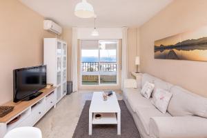 a living room with a white couch and a tv at Sunshine Balcony- La Caleta in Caleta De Velez