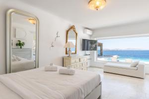 una camera bianca con un grande letto e un grande specchio di Villa Deloxenia by Ethos Hospitality a Mykonos Città Altre 42 foto