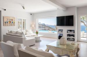 un soggiorno con mobili bianchi e una grande finestra di Villa Deloxenia by Ethos Hospitality a Mykonos Città