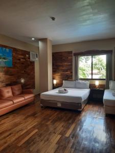 Mabini Hotel في مامباجاو: غرفة نوم كبيرة مع سرير وأريكة