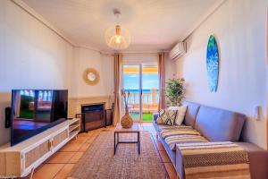 een woonkamer met een bank en een flatscreen-tv bij Primera linea de playa , increíbles vistas, amplio in La Mata