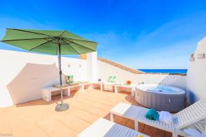 een patio met een hot tub en een parasol bij Primera linea de playa , increíbles vistas, amplio in La Mata