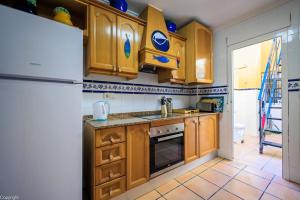 a kitchen with wooden cabinets and a white refrigerator at Primera linea de playa , increíbles vistas, amplio in La Mata