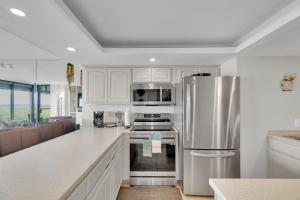 a kitchen with white cabinets and a stainless steel refrigerator at Sea Vista in South Padre Island