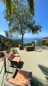 um pátio com cadeiras e uma árvore com vista em Alto da Piraquara Flat em Angra dos Reis