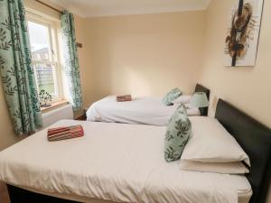 two twin beds in a room with a window at Bank Top Cottage in Embleton +26 photos