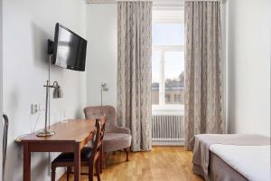 ein Hotelzimmer mit einem Schreibtisch, einem Stuhl und einem Fenster in der Unterkunft Amals Stadshotell, Sure Hotel Collection by Best Western in Åmål