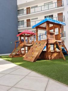 um parque infantil de madeira com um escorrega em frente a um edifício em Departamento en el corazón de Guadalajara em Guadalajara