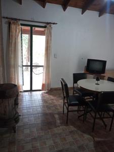 a living room with a table and chairs and a television at Cabaña en quinta la aurora in Mina Clavero