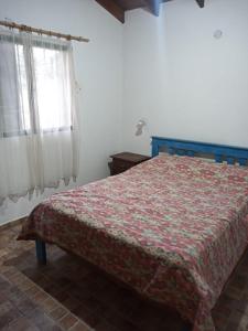 a bedroom with a bed with a red blanket and a window at Cabaña en quinta la aurora in Mina Clavero