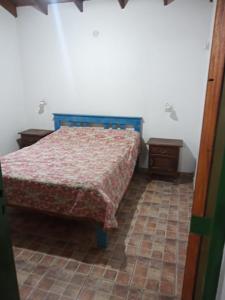 una camera con letto e pavimento piastrellato di Cabaña en quinta la aurora a Mina Clavero