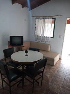un soggiorno con tavolo, sedie e divano di Cabaña en quinta la aurora a Mina Clavero