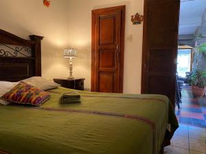 a bedroom with a bed with a green bedspread at Hotel Cristal in Antigua Guatemala