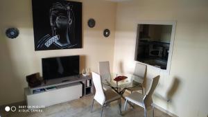 a dining room with a glass table and a television at Residencial La Duquesa Suites Golf & Gardens in San Luis de Sabinillas