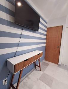ein Wohnzimmer mit einem TV an einer gestreiften Wand in der Unterkunft Condominio del faro frente a playa in Nuevo Vallarta