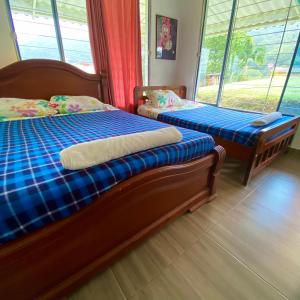 two beds in a room with two windows at Finca Villa Anita Moniquirá Boyacá in Moniquirá