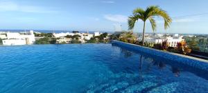 a swimming pool with a palm tree and a city at Menesse mitdtown2 , AVE 25TH in Playa del Carmen