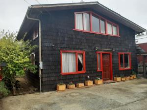 una casa negra con ventanas rojas y una puerta roja en Wool & Wood House en Puerto Varas