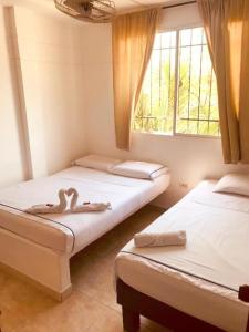 Dos camas en una habitación con dos cisnes. en CasaHotelMarly en Santa Marta