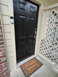 eine schwarze Tür mit einer Willkommensmatte davor in der Unterkunft Home Away From Home-Cozy 2 BDRM Condo/Med Cntr/NRG in Houston