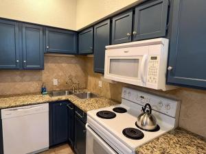 a kitchen with blue cabinets and a white stove and microwave at Home Away From Home-Cozy 2 BDRM Condo/Med Cntr/NRG in Houston