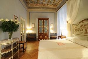 ein Schlafzimmer mit einem Bett und einem Tisch mit einer Blumenvase in der Unterkunft Palazzo Rocchi B&B in Lucca