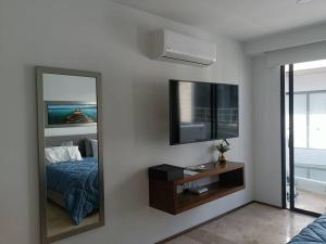 a mirror in a room with a bed and a television at Menesse mitdtown2 , AVE 25TH in Playa del Carmen