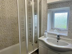 a white bathroom with a sink and a window at North Wales Holiday Accomodation with Free parking & WiFi in Bodelwyddan