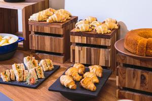 a bunch of different types of bread and pastries on plates at Novotel Lencois Paulista in Lençóis Paulista