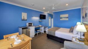 Pokój hotelowy z łóżkiem i niebieską ścianą w obiekcie Colonial Motel & Apartments w mieście Young