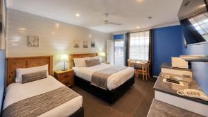 um quarto de hotel com duas camas e uma secretária em Colonial Motel & Apartments em Young