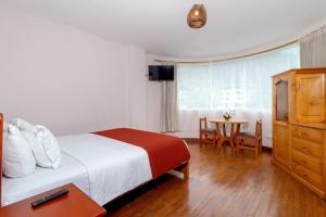 une chambre d'hôtel avec un lit et une table avec des chaises dans l'établissement Napolitano Apart Hotel, à Baños