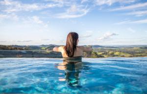 a woman standing in a infinity pool in the water at Sierra Escape Luxury Glamping in Piambong