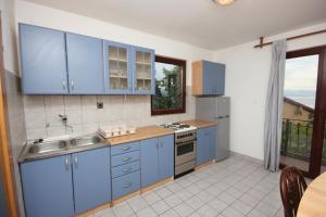 uma cozinha com armários azuis e um lavatório em Apartments with a parking space Opatija - 7904 em Opatija