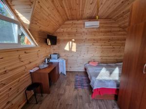 1 dormitorio en una cabaña de madera con cama y escritorio en Шафран, en Krasnaya Slobodka
