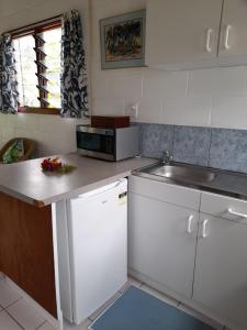 a kitchen with white cabinets and a sink and a counter at Reefcomber Sunset Beach in Rarotonga