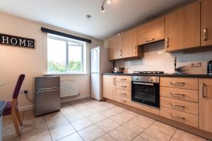 a large kitchen with wooden cabinets and a window at Cheerful 4 Bedroom townhouse with free parking in Exhall