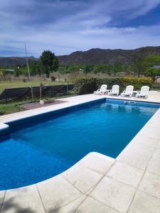 a swimming pool with white chairs next to at Die Lavendel Chalet in Villa General Belgrano