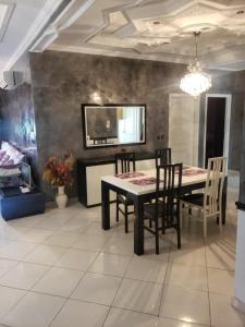 a dining room with a black table and chairs at Appartement meublé haut standing in Fez