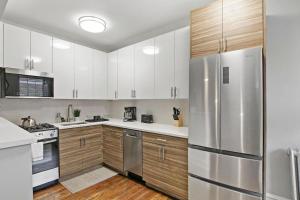 a kitchen with white cabinets and a stainless steel refrigerator at Adorable 1BR Apt in Evanston with Onsite Laundry - Elmwood 105 in Evanston