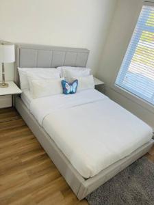 Una cama blanca con una mariposa azul sentada encima. en Gorgeous 3 bedroom lake house Suite!, en Shawnigan Lake