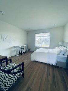 1 dormitorio con cama blanca, escritorio y ventana en Gorgeous 3 bedroom lake house Suite!, en Shawnigan Lake