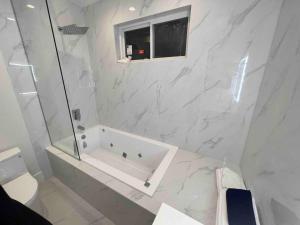 baño blanco con bañera y ventana en Gorgeous 3 bedroom lake house Suite!, en Shawnigan Lake