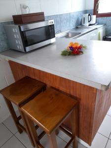 a kitchen counter with a microwave and flowers on it at Reefcomber Sunset Beach in Rarotonga