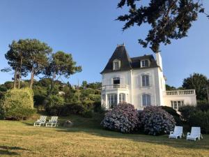 une grande maison blanche avec des chaises dans la cour dans l'établissement Villa Plougasnou - BRE05110i-O, à Plougasnou