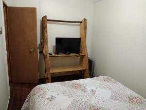 1 dormitorio con 1 cama y TV en una silla en Hostal Doña Ema, en Pisco Elqui