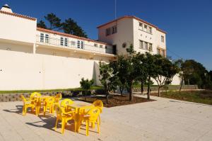 eine Gruppe gelber Tische und Stühle vor einem Gebäude in der Unterkunft HI Alfeizerão – Pousada de Juventude in Alfeizerão