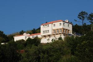 ein weißes Haus auf einem Hügel in der Unterkunft HI Alfeizerão – Pousada de Juventude in Alfeizerão